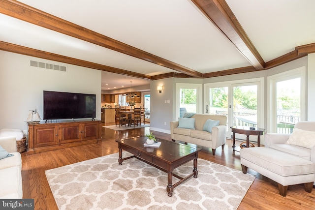 living room featuring beam ceiling, light wood-style floors, and ornamental molding
