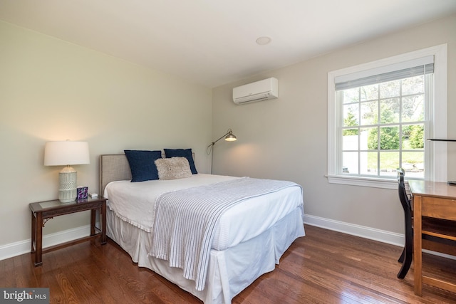 bedroom featuring a wall mounted AC, wood finished floors, and baseboards