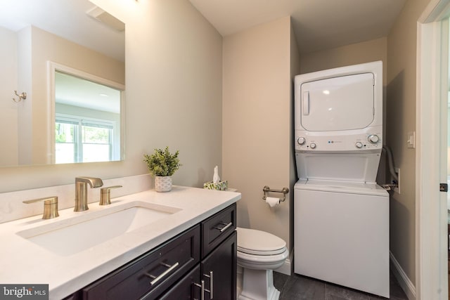 bathroom featuring estacked washer and dryer, toilet, vanity, and wood finished floors