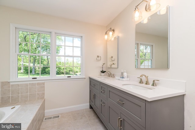bathroom featuring baseboards, double vanity, tiled tub, and tile patterned flooring
