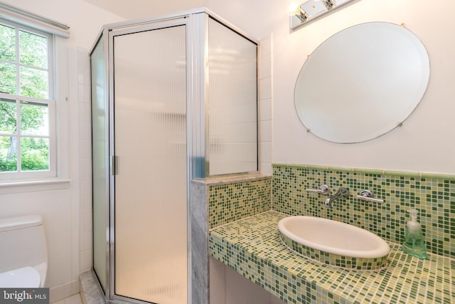 bathroom featuring a stall shower, toilet, and a sink