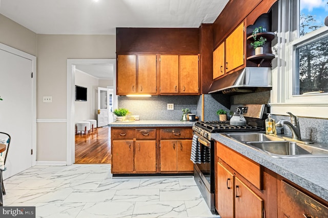 kitchen with a sink, brown cabinets, stainless steel gas stove, and under cabinet range hood