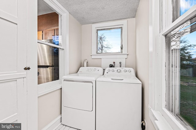 laundry area featuring baseboards, laundry area, washing machine and clothes dryer, and a textured ceiling