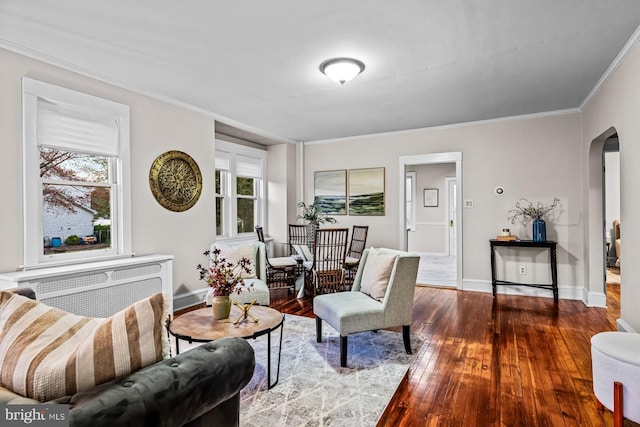 living area with arched walkways, wood-type flooring, ornamental molding, and baseboards