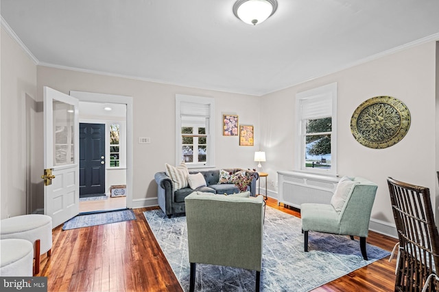 living area featuring crown molding, radiator, baseboards, and hardwood / wood-style flooring