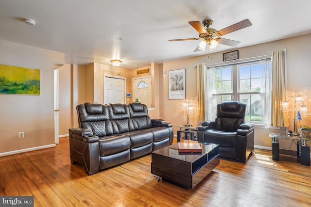 living area with a ceiling fan, light wood-style flooring, and baseboards