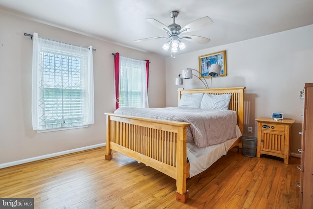 bedroom with a ceiling fan, wood finished floors, and baseboards