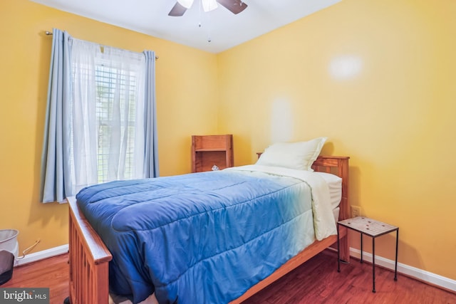 bedroom featuring wood finished floors, baseboards, and multiple windows