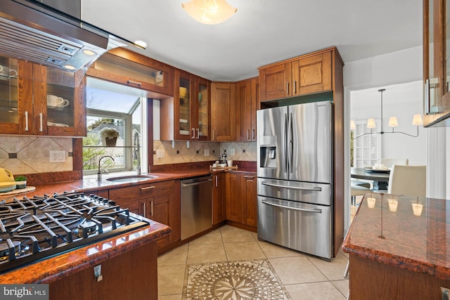 kitchen with dark stone counters, light tile patterned floors, brown cabinets, glass insert cabinets, and stainless steel appliances