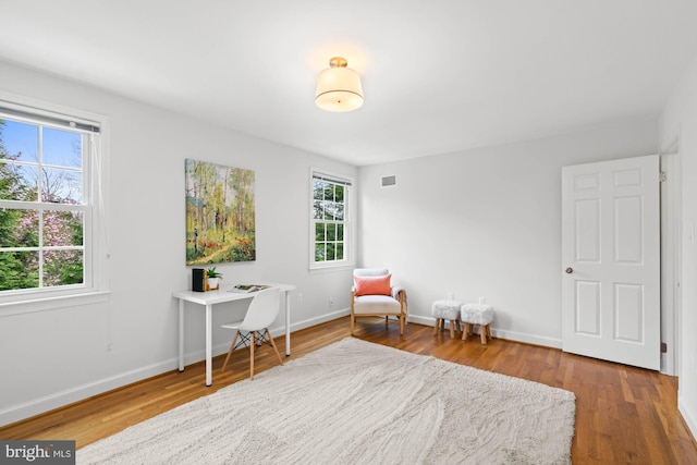 living area featuring visible vents, wood finished floors, and baseboards