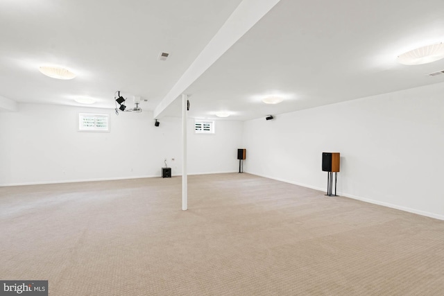 basement featuring light colored carpet, visible vents, and baseboards