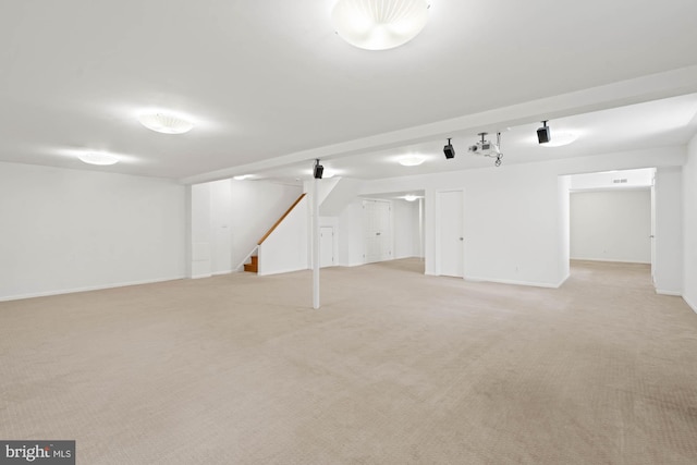 finished basement with stairs, light carpet, and baseboards