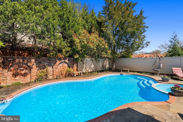 view of pool featuring a patio, a fenced backyard, and a pool with connected hot tub