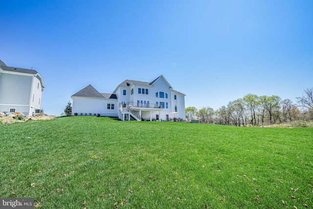 rear view of property with stairs and a lawn