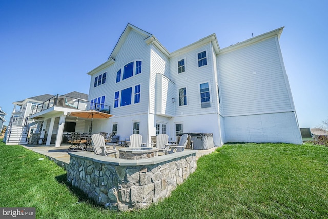 rear view of house with a yard, a fire pit, a balcony, and a patio