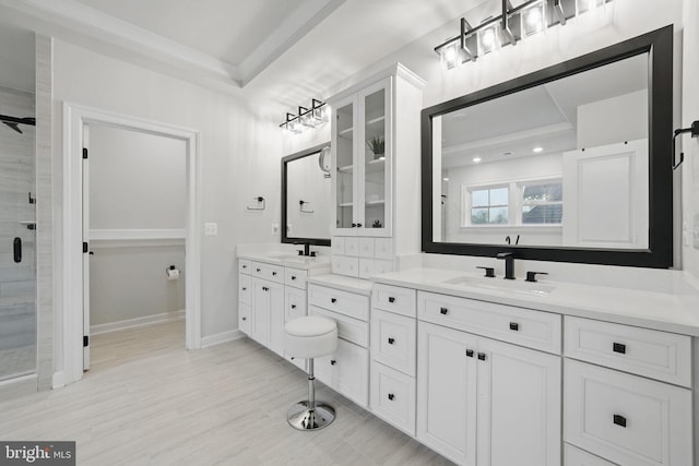 full bathroom with two vanities, baseboards, a sink, and a stall shower