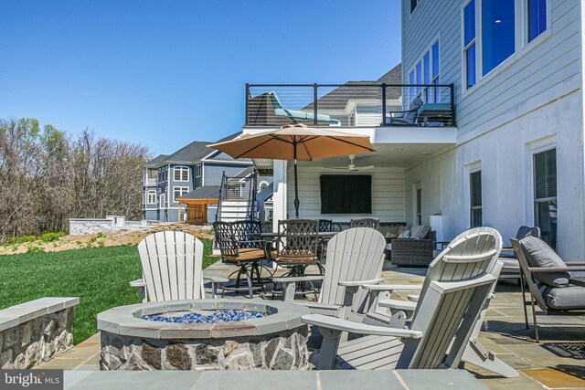 view of patio featuring a balcony, a ceiling fan, and an outdoor fire pit