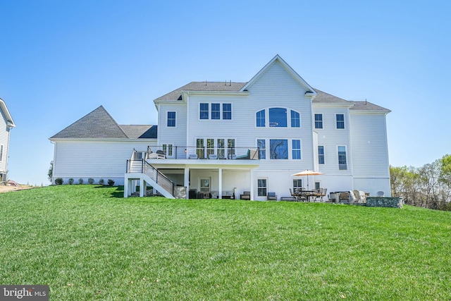 rear view of property featuring a lawn, a deck, and stairs