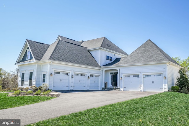 view of front of house featuring roof with shingles, driveway, a garage, and a front lawn