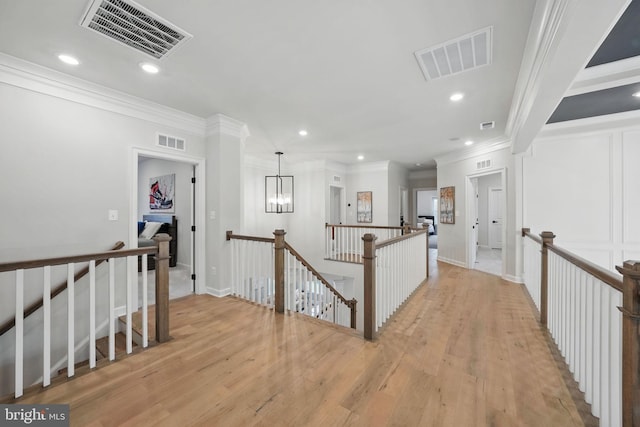 hall with an upstairs landing, visible vents, and crown molding