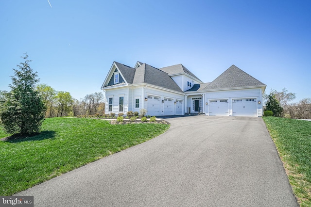 view of front facade with roof with shingles, an attached garage, driveway, and a front lawn