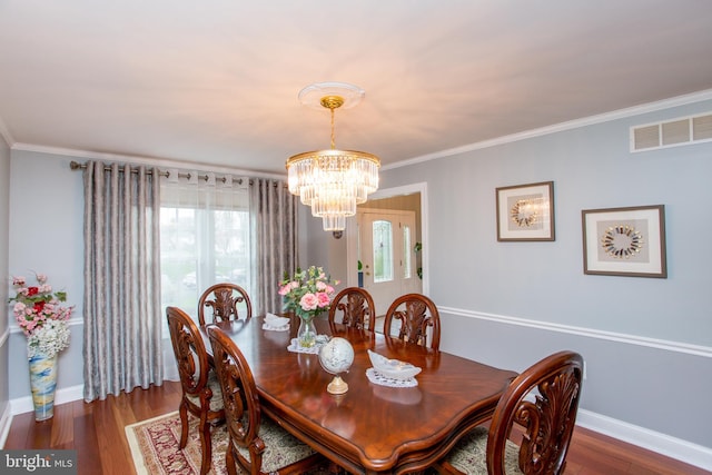 dining room featuring ornamental molding, visible vents, a chandelier, wood finished floors, and baseboards