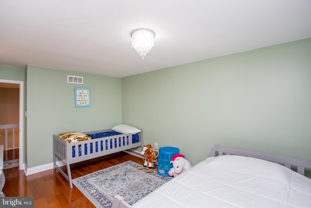 bedroom featuring visible vents, baseboards, and wood finished floors