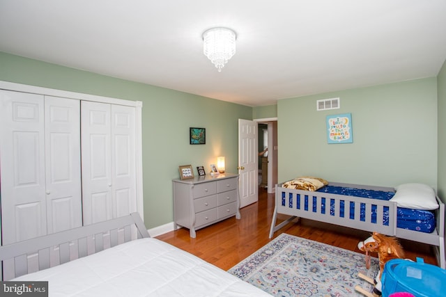 bedroom with visible vents, baseboards, a closet, and wood finished floors