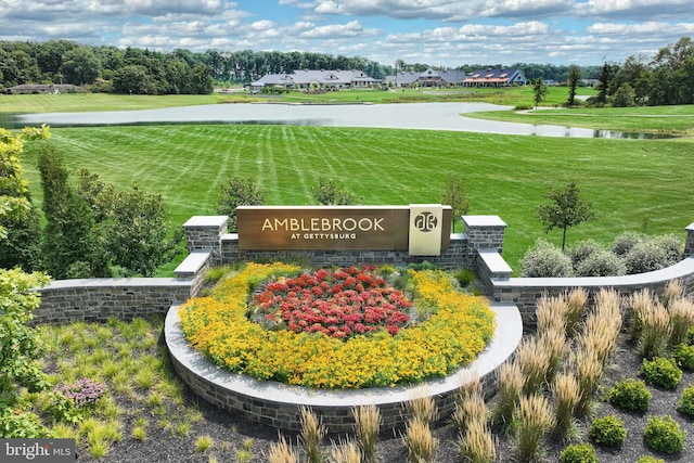 community sign featuring a yard and a water view