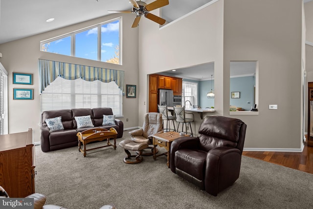 living room with carpet floors, baseboards, a ceiling fan, and high vaulted ceiling