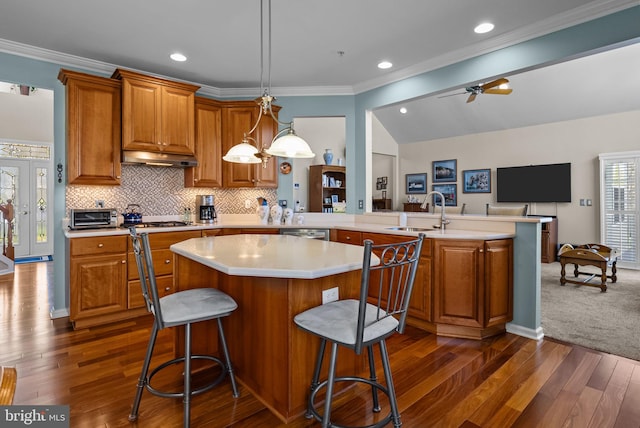 kitchen featuring a sink, brown cabinets, light countertops, dark wood-style floors, and a kitchen island