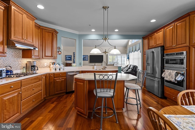kitchen featuring dark wood-style flooring, light countertops, appliances with stainless steel finishes, and under cabinet range hood