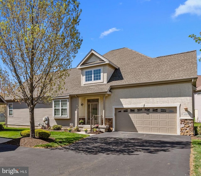 traditional home with aphalt driveway, an attached garage, stone siding, stucco siding, and a shingled roof