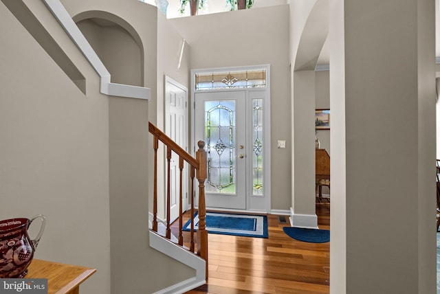 foyer entrance featuring stairway, a high ceiling, plenty of natural light, and wood finished floors