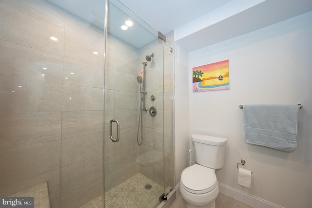 bathroom featuring toilet, a shower stall, and baseboards