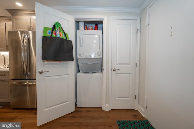 laundry area with stacked washing maching and dryer, laundry area, crown molding, and wood finished floors