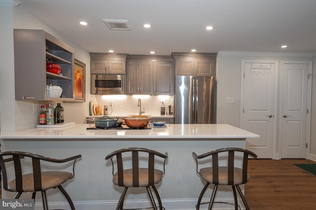 kitchen with visible vents, light countertops, a kitchen breakfast bar, a peninsula, and stainless steel appliances