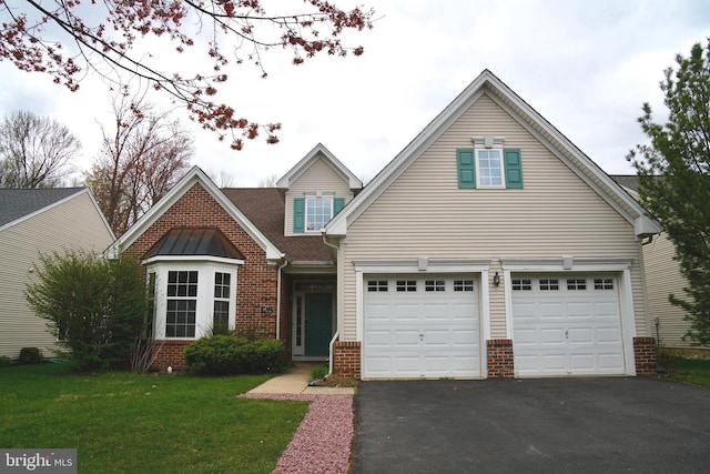 view of front of home featuring a garage, aphalt driveway, brick siding, and a front yard
