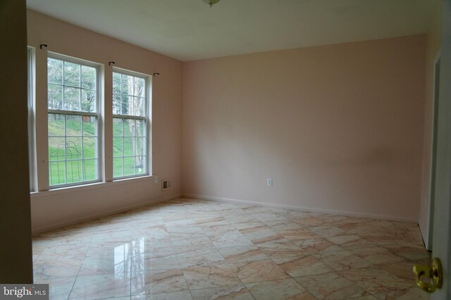 unfurnished room featuring baseboards, visible vents, and a wealth of natural light