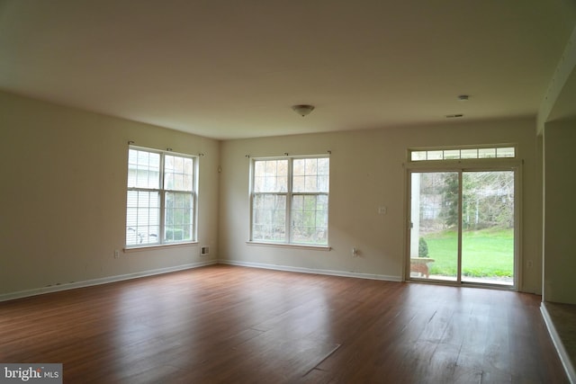 unfurnished room featuring baseboards and dark wood finished floors