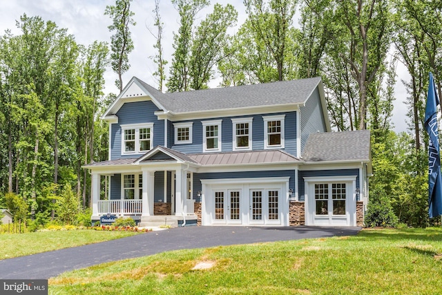 view of front of home featuring a front yard, a standing seam roof, metal roof, french doors, and driveway