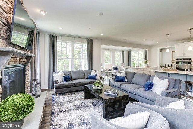 living room featuring wood finished floors, recessed lighting, a stone fireplace, and a healthy amount of sunlight