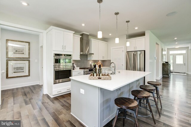 kitchen with decorative backsplash, wall chimney exhaust hood, white cabinetry, and stainless steel appliances
