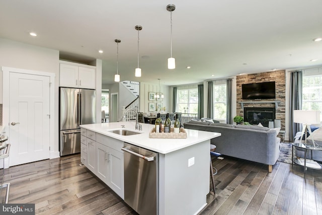 kitchen with open floor plan, dark wood-style floors, white cabinets, appliances with stainless steel finishes, and a sink