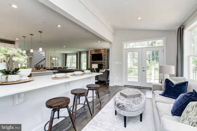 living room with a wealth of natural light, recessed lighting, dark wood-style floors, and french doors