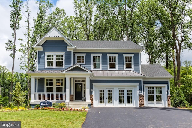view of front of property featuring a standing seam roof, metal roof, a front yard, stone siding, and french doors