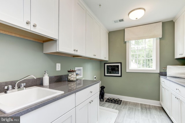laundry area with baseboards, visible vents, hookup for a washing machine, cabinet space, and a sink