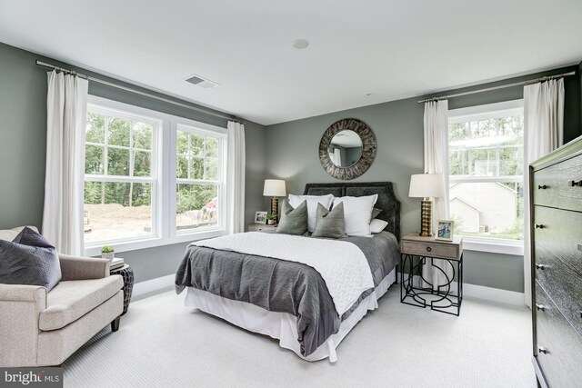 carpeted bedroom featuring baseboards, multiple windows, and visible vents