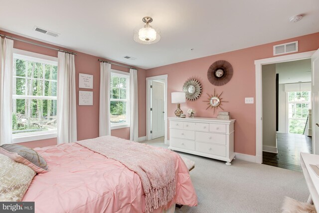 bedroom with visible vents, baseboards, and light carpet