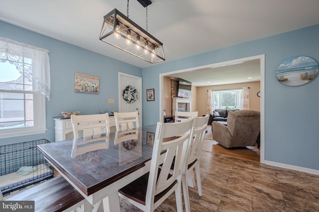 dining room featuring a fireplace, a wealth of natural light, and baseboards